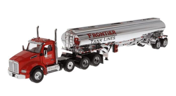 A red and silver truck is parked next to the tanker.