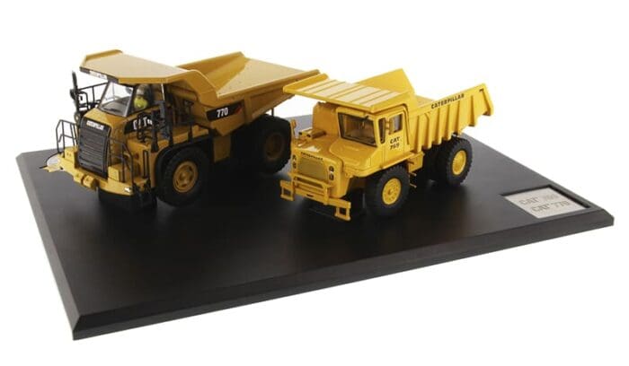 A yellow dump truck and a black cat truck on display.