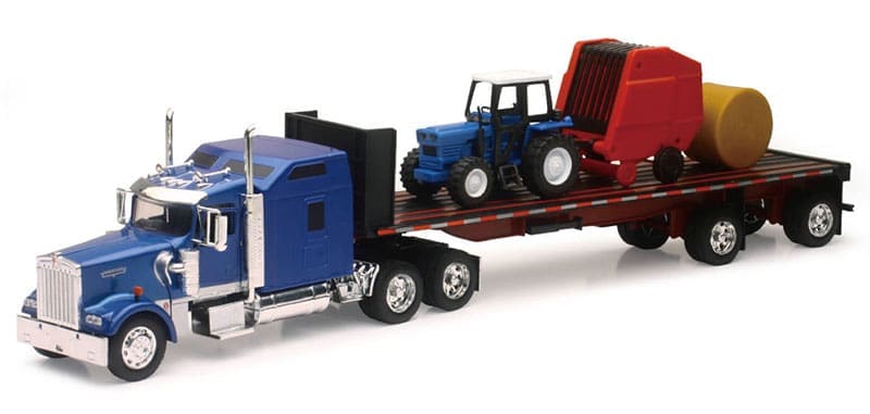 A tractor trailer hauling a large red and blue tractor.