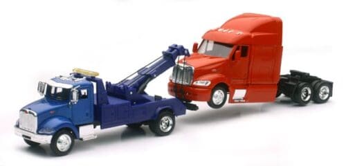 A tow truck towing a red semi-truck.