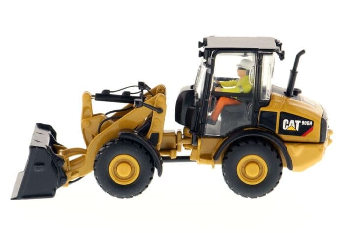 A yellow and black cat wheel loader with a man sitting in the cab.