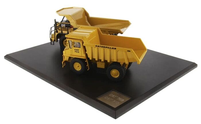 A yellow dump truck on display with a plaque.