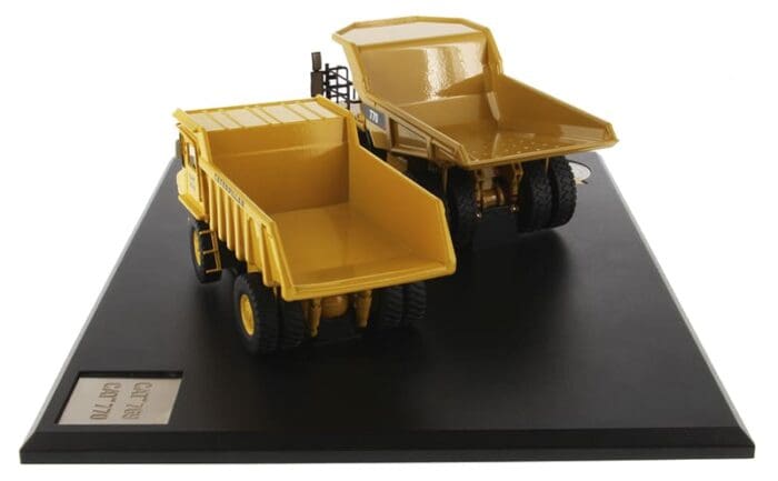 A yellow dump truck on display next to another one.
