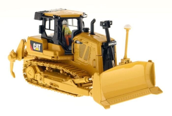 A yellow cat bulldozer with a worker on the front.