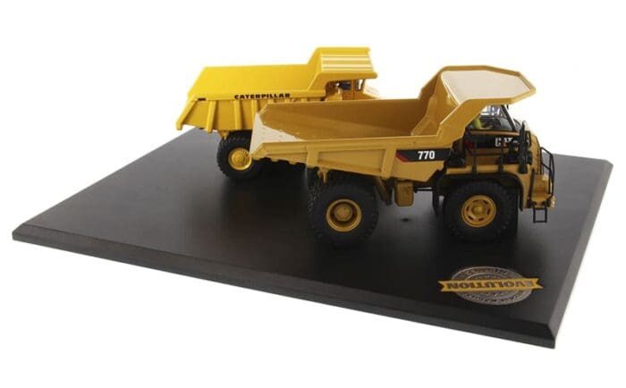 A yellow dump truck on display with black base.