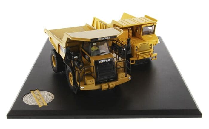 A yellow dump truck on display on top of a black table.