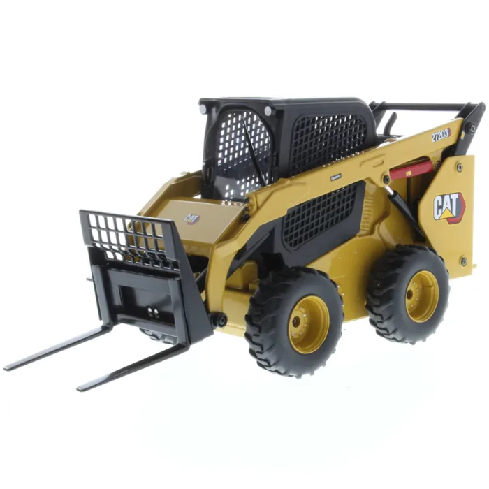 A yellow cat skid steer with a fork in the back.